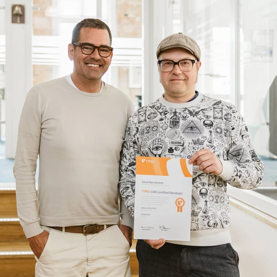 Ein echter TYPO Hochzwei Geschäftsführer Felix mit unserem Kollegen, der sein Typo3 Zertifikat in die Kamera hält.