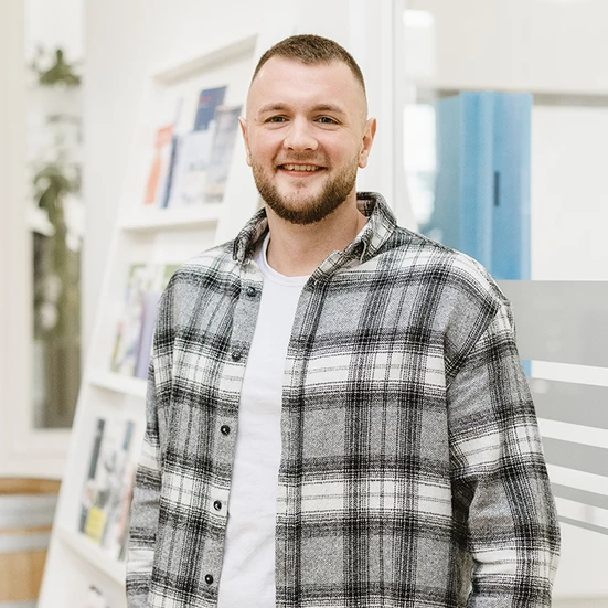 Nils-Rasmus Jochimsen Portrait von Nils-Rasmus Jochimsen. Er lächelt in die Kamera und trägt ein weiß-graues Flanellhemd und ein weißes T-Shirt.